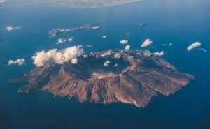 Aerial view over Nisyros island, Greece. Nisyros is a volcanic Greek island and municipality located in the Aegean Sea. It is part of the Dodecanese group of islands, situated between the islands of Kos and Tilos.
Its shape is approximately round, with a diameter of about 8 km and an area of 41.6 km2. Several other islets are found in the direct vicinity of Nisyros, the largest of which is Gyali, with a population of 22 citizens.